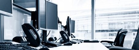 Büro Schreibtisch mit mehreren Computermonitoren und einer Tastatur.